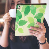 a girl is holding and viewing personalized iPad folio case with Leaves design 